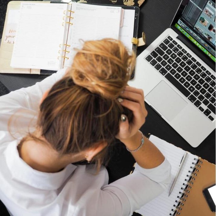 Vrouw met het hoofd in de handen aan een bureau